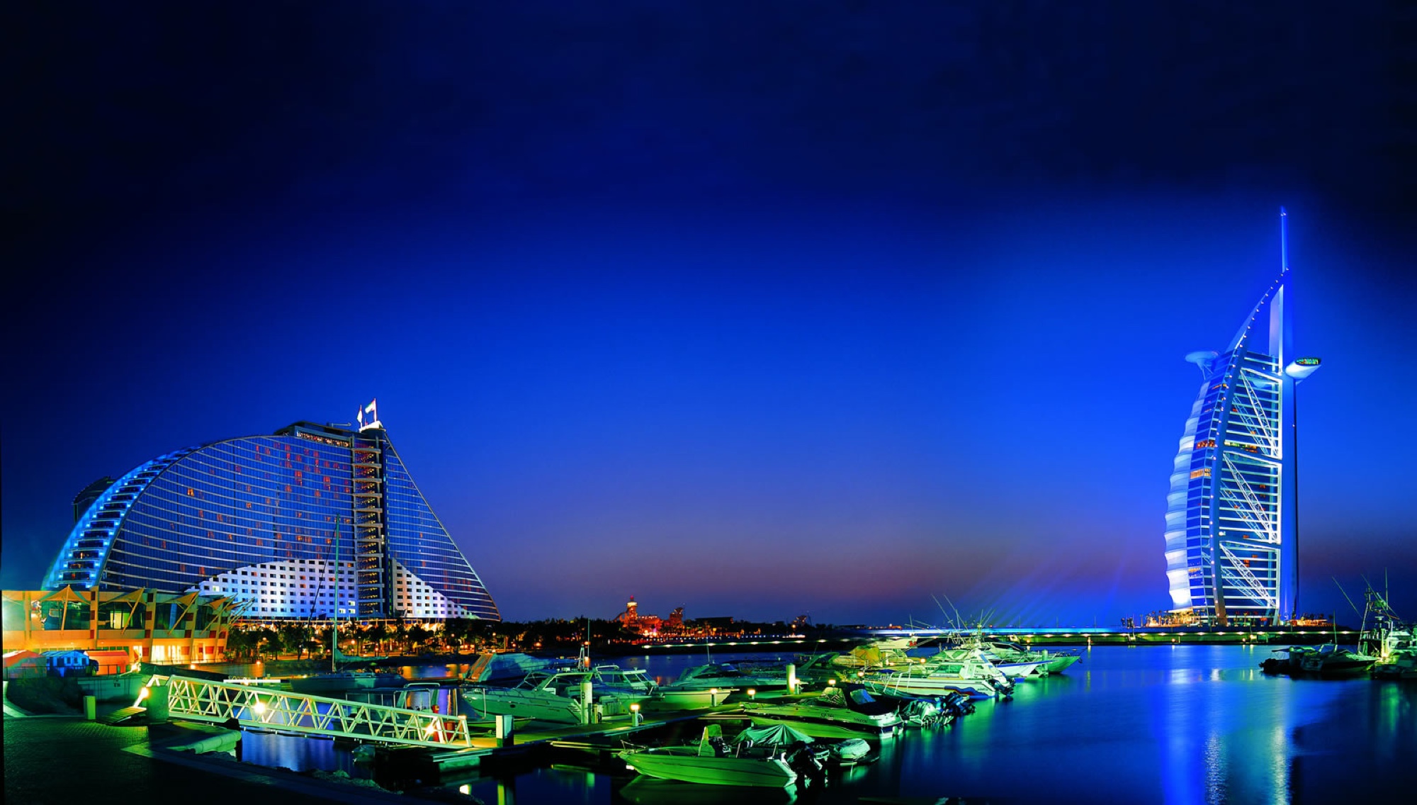 The Burj Al Arab and Jumeirah Beach Hotel lit at blue hour above a Dubai marina